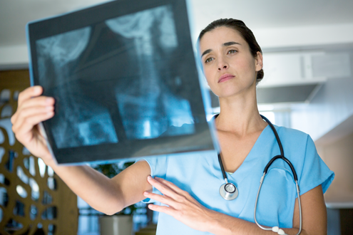 Nurse looking at x-ray of a patient's spine.